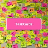 Viele beschriebende Klebezettel an einer Wand und Schrift TaskCards