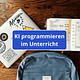 Laptop, Notizbuch und Rucksack auf einem Tisch, Schrift KI im Unterricht