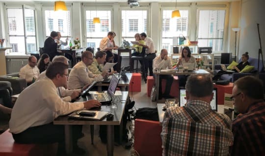 Menschen am Tisch mit Laptops im Raum